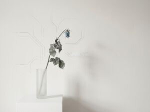 Verwelkte plant met hangende bloem op witte achtergrond, minimalistische compositie die vermoeidheid en uitputting symboliseert