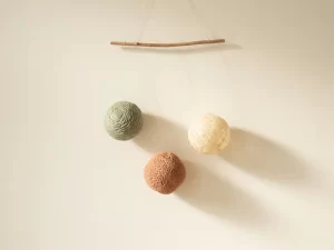 Drie organische sferen in salie, terracotta en ivoor hangen in balans aan fijne draden, symbool voor darm, hormonen en zenuwstelsel.